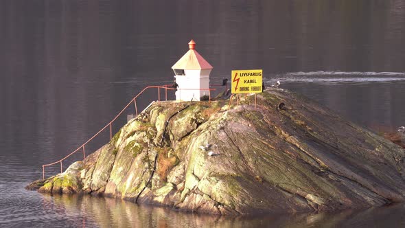 Two great cormorants drying their wings on a lighthouse island in western Norway while another cormo