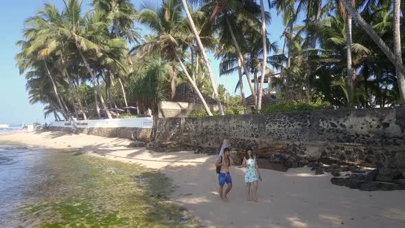 Couple with Kid Wander Along Sandy Coastline Near Ocean