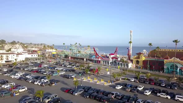 Parking area cars palms, amusement park, roller coaster. Stunning aerial view flight sinking down dr