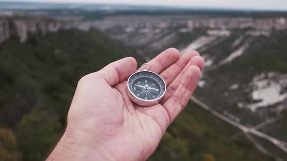 Hiker Man Searching Direction with a Compass in Mountain Valley