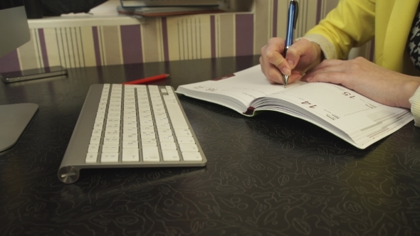 A Student In a Yellow Jacket Writing In a Notebook alt
