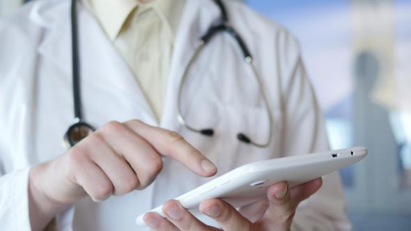 Doctor Working On Tablet Computer In Hospital