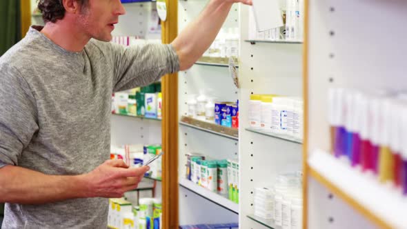 Customer using mobile phone with a bottle of drug in hand