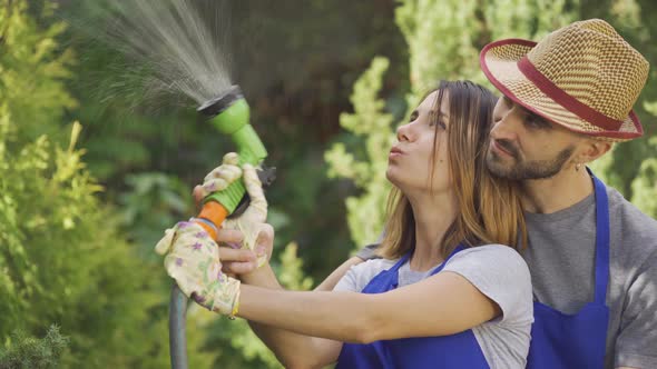 Portrait of Attractive Caucasian Woman and Man in Blue Uniform Playing with Water Hose