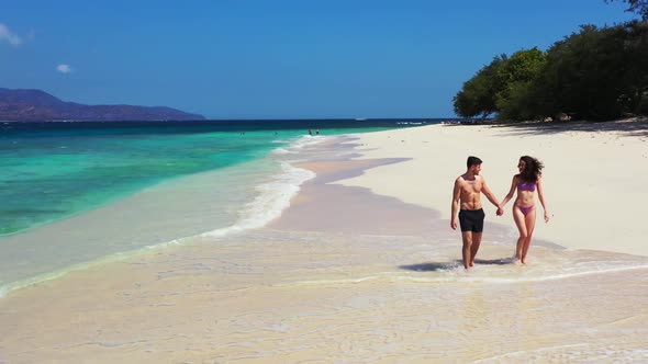 Young couple relax on marine sea view beach time by blue lagoon and white sandy background of Gili M