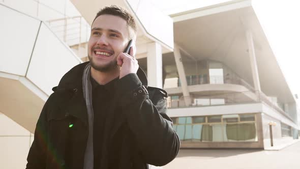 Handsome Young Caucasian Male Talking on Mobile Phone Standing Outdoors