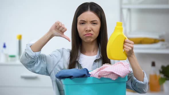 Woman With Basket Full of Clothes and Laundry Detergent Showing Thumbs-Down