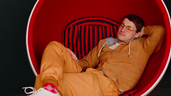 Tired Man in Glasses Reclining in Round Chair