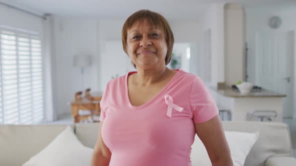 Portrait of smiling african american senior woman wearing pink t shirt and pink breast cancer ribbon