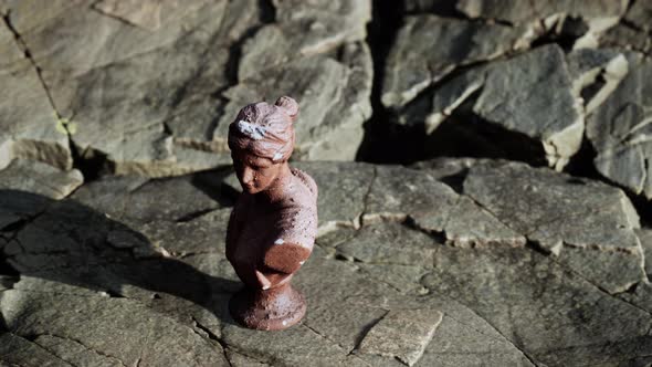 Ancient Statue of Woman on Rocky Stones alt