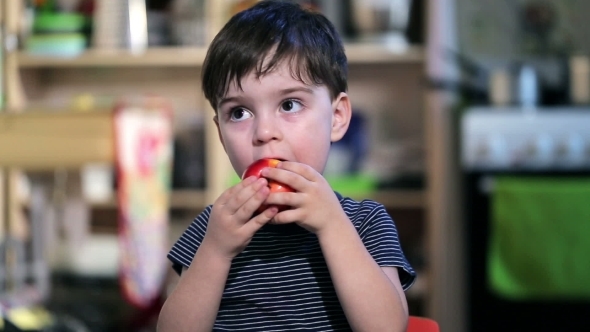 Cheerful Boy In a Striped Shirt Eating An Apple
