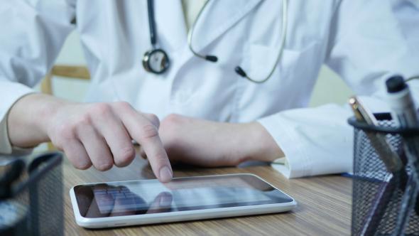 Doctor Typing On Tablet In Hospital