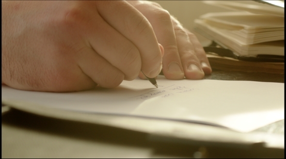 Man Writing On The Paper With Pen