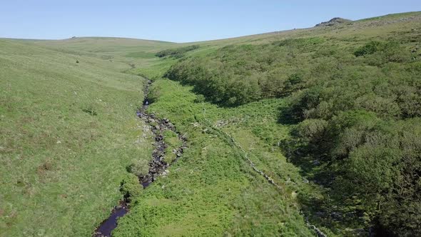 Wide aerial shot tracking upwards, with wistmans wood, a river and grassy moorland setting the scene