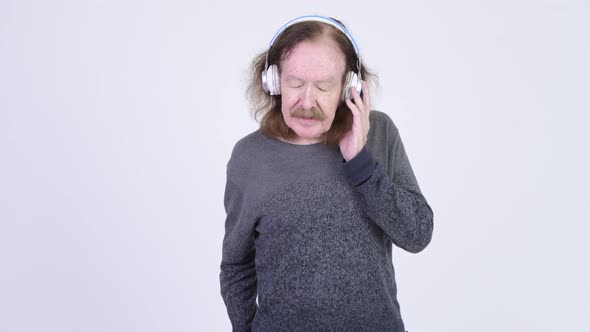 Senior Man with Mustache Listening To Music