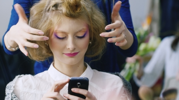 Beautiful Woman Enjoys The Smartphone In a Beauty Salon