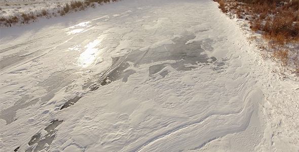 Aerial View of Frozen River with Snowy Banks