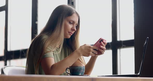 Woman Reading Messages on Smartphone Sitting in a Cafe