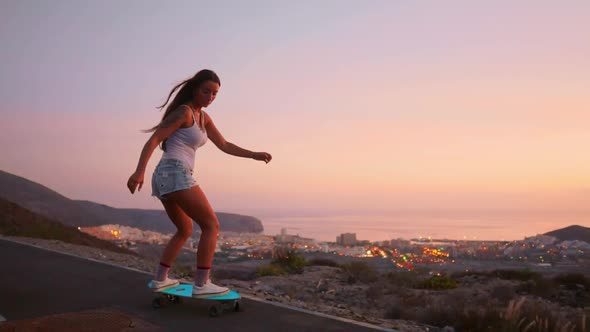 Beautiful Girl Rides a Skateboard on the Road Against the Sunset Sky