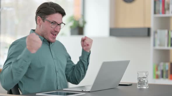 Middle Aged Man Celebrating Success While Using Laptop