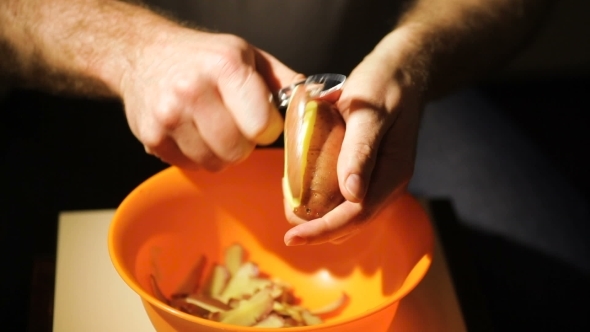 Man Peeling  Potatoes In Kitchen For Prepare Food