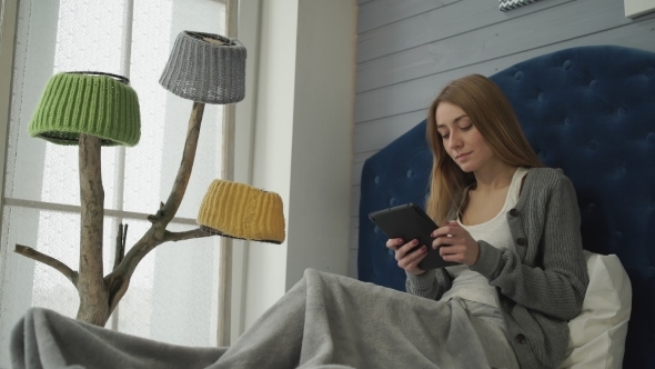 Woman Sitting On a Bed With a Tablet.