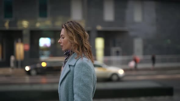 Melancholic Frustrated Woman is Walking Alone on City Street Looking on Grey Buildings