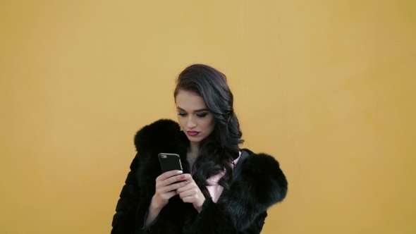 Pretty Lady In The Fur Using Smartphone And Looking On The Sky