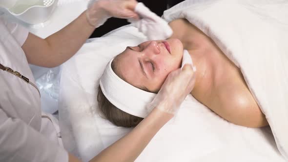 The Cosmetologist Cleanses the Client's Face and Neck with Cosmetic Napkins