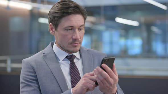 Portrait of Middle Aged Businessman using Smartphone