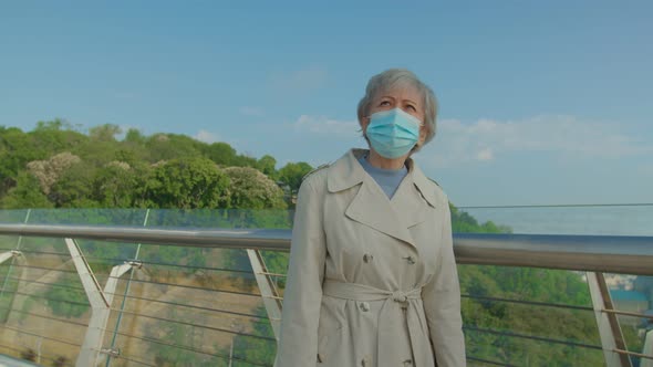 Senior Vaccinated Woman Putting Off Medical Mask Outdoors