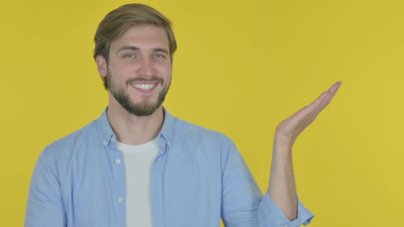 Young Man Showing on Side on Yellow Background