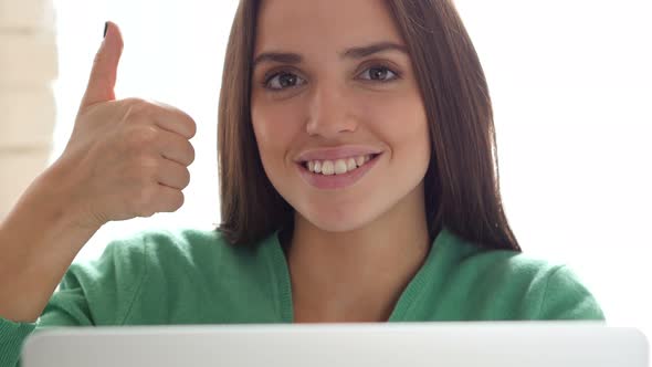 Thumbs Up by Creative Woman Sitting on Her Desk