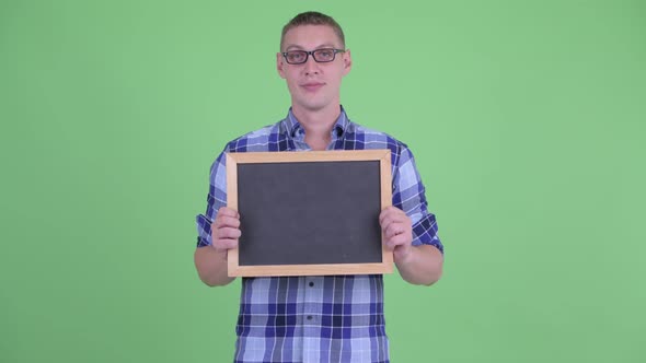 Happy Young Hipster Man Thinking While Holding Blackboard