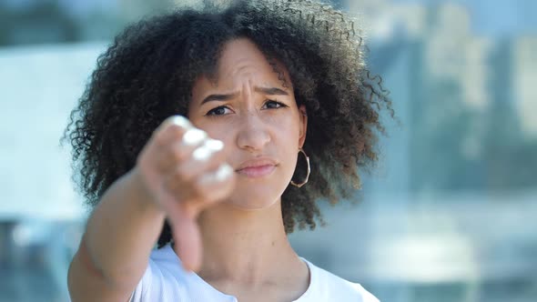 Young Beautiful African American Woman Holds Out Hands, Gives Thumbs Down Gesture of Frustration and