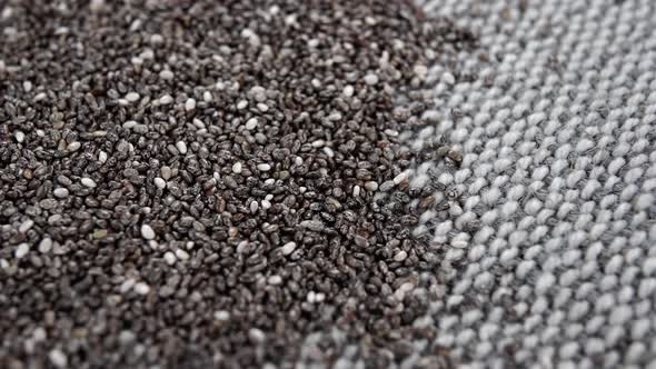 A pile of dry chia seeds on a gray rustic rough jute fabric. Macro