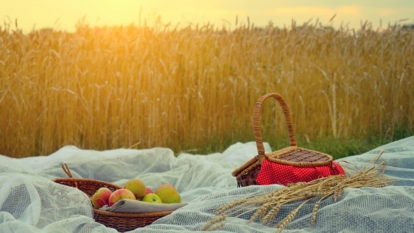 Composition With Handmade Wicker Basket, Apples And Branch Of Wheat On Cloth And Placed In Wheat