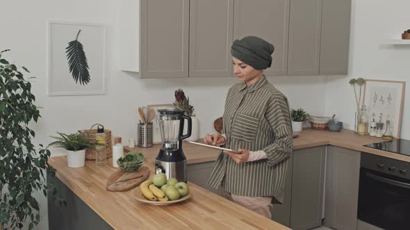 Muslim Woman Using Digital Tablet in Kitchen at Home