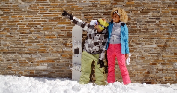 Snowboarder With Happy Friend Pointing Upwards