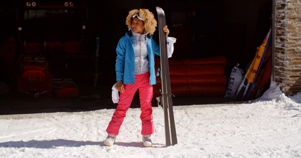 Confident Young Woman In Snowsuit With Skis