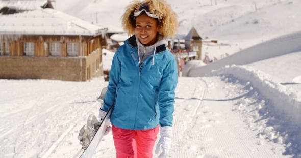 Smiling Pretty Young Woman Carrying a Snowboard