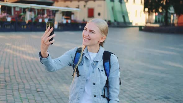 }Female Tourist Making Video Call on Smartphone From the Place of Her Visit