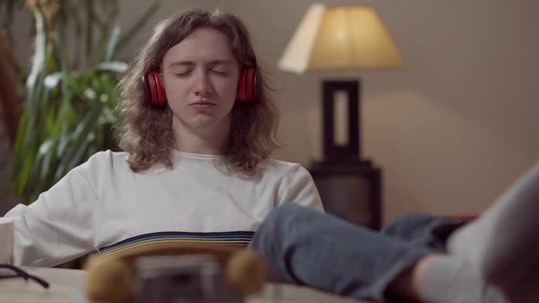 Portrait of Happy Relaxed Young Man in Headphones with Closed Eyes Listening to Music Imitating