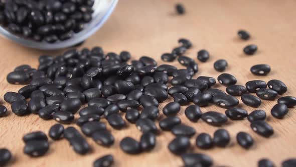 Slow motion black beans closeup falling from white bowl 