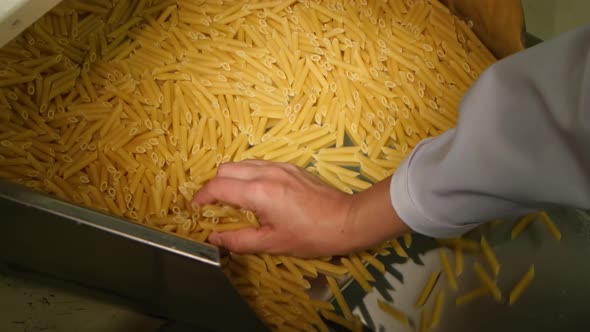 Mans Hand Takes Handful of Pasta From Production Line