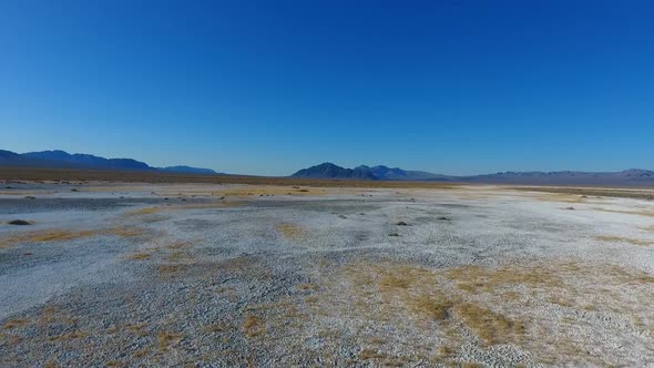 Flying Across Stunning White Desert Sand Landscapes Towards Mountains