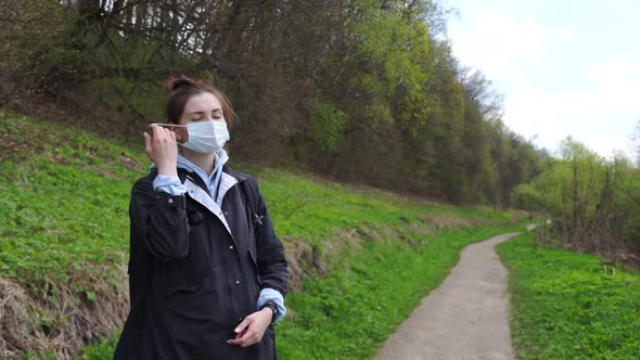 Woman in Park Takes Off Protective Mask From Her Face and Breathes in Air Deeply