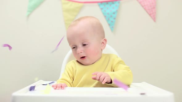 Baby boy sitting in highchair with bunting