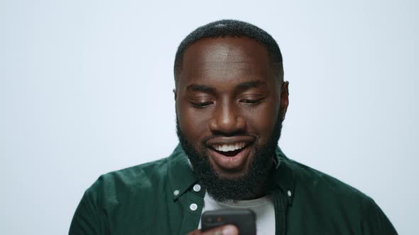 Portrait of Emotional African Man Looking Smartphone Screen in Grey Background