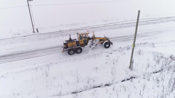 Aerial view of Snowblower Grader Clears Snow Covered Country Road in village 05